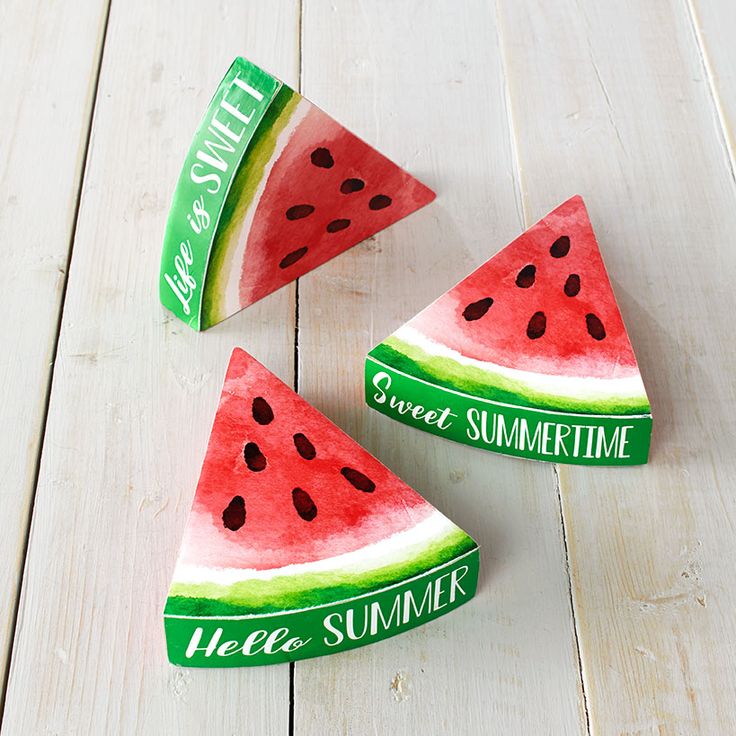 three slices of watermelon sitting on top of a white wooden table next to each other