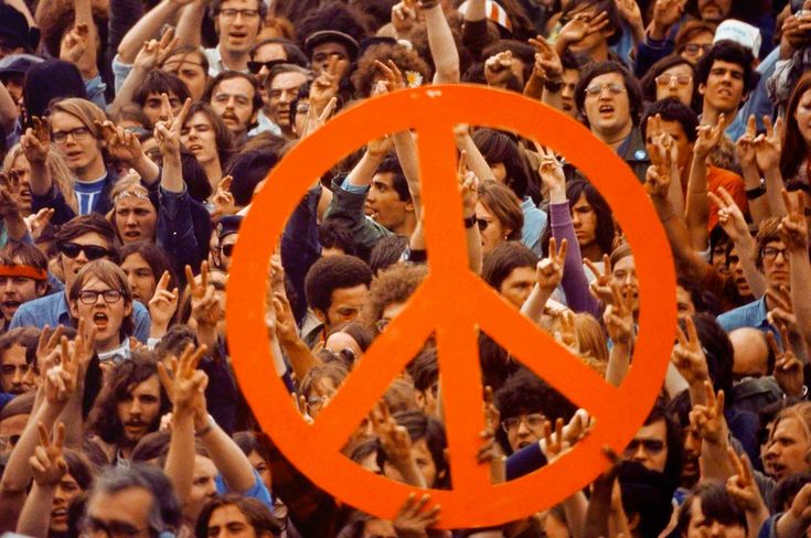 a large group of people holding up peace signs