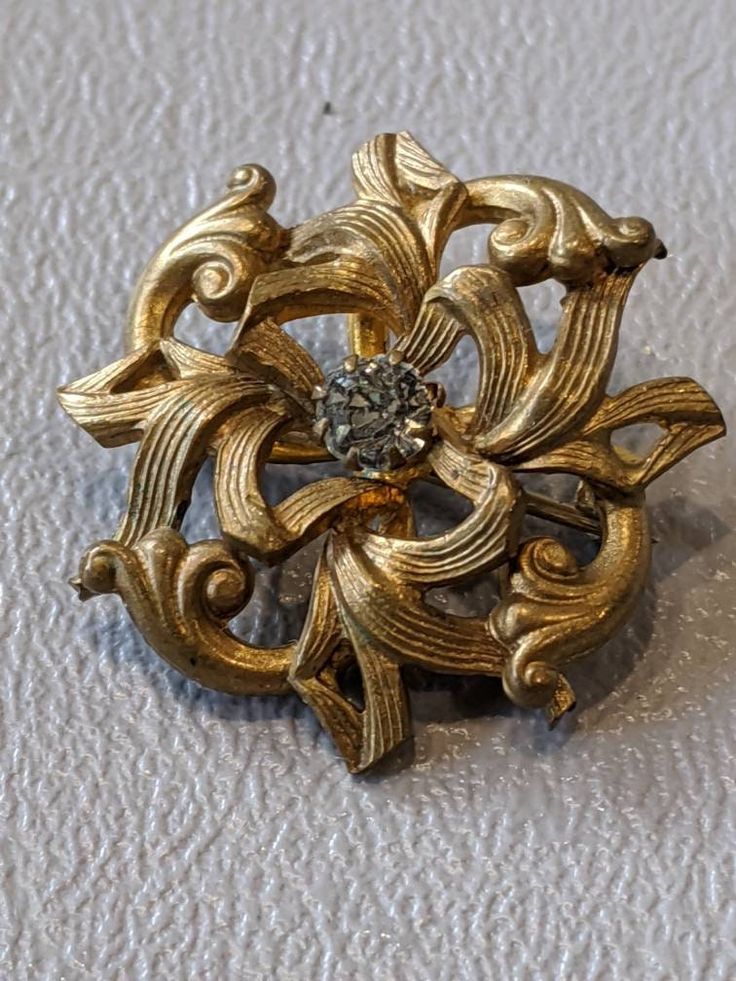 "Victorian Gold Filled Diamond Paste Pin Antique ornate gold filled pin featuring Diamond paste prong set from the early Victorian era. C-clasp closure is in good working order. Stone is original to piece. Pin will arrive gift boxed. * HALLMARKS Unmarked. * SIZE/MEASUREMENTS 1 1/8\" x 1 1/8\" * CONDITION In good to excellent condition for age of piece. Please use all pictures as part of item's description. * MATERIALS Gold filled, Paste." Ornate Yellow Gold Brooch For Formal Occasions, Antique Yellow Gold Brooches With Intricate Design, Antique Yellow Gold Filigree Brooches, Vintage Yellow Gold Jewelry With Clasp, Heirloom Gold Brooch With Intricate Design, Gold Art Deco Brooch For Evening, Gold Art Deco Brooches For Evening, Heirloom Gold Brooches With Intricate Design, Heirloom Gold Brooches For Evening