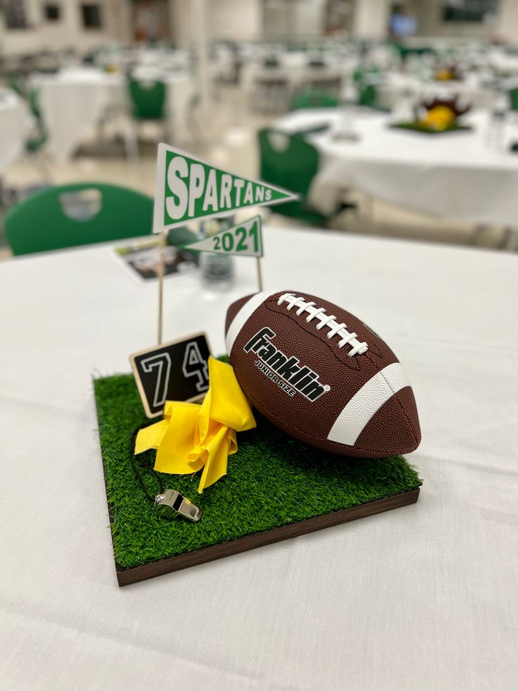 a football on top of a table at a sports themed party with yellow flowers in the grass