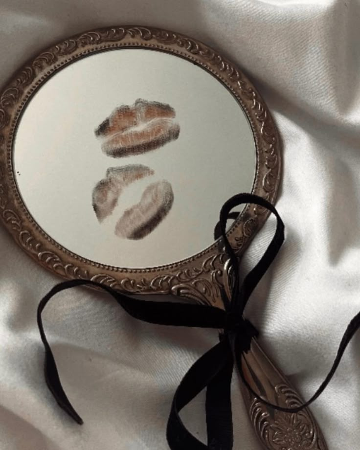 a mirror with two hand prints on it sitting on a white cloth covered bed sheet