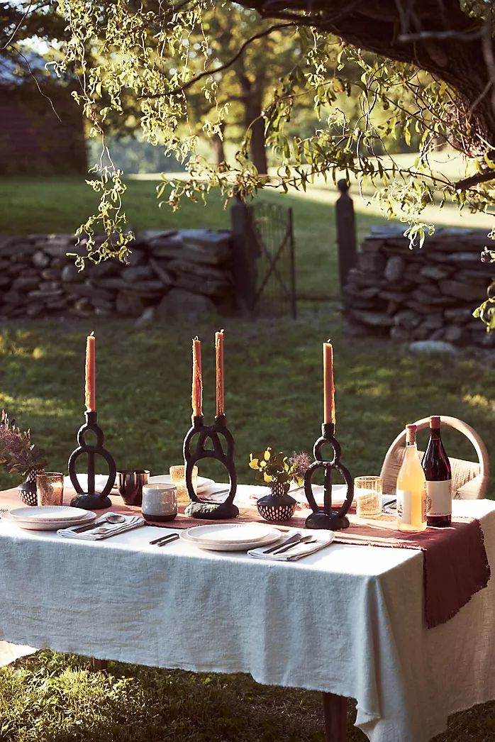 the table is set with wine bottles and candles for an outdoor dinner in the garden