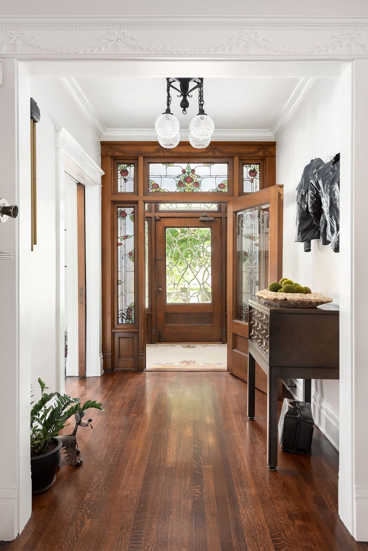 an entryway with wood floors and glass doors, potted plants on the table