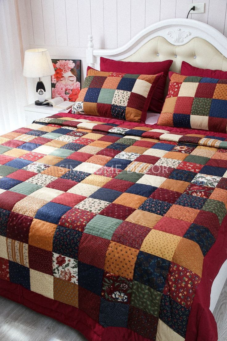 a bed with a red and blue quilted comforter on it's side