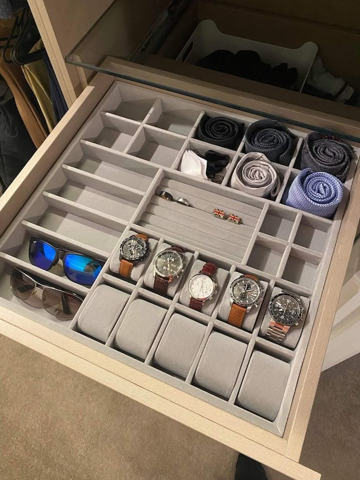 an open drawer with several watches and ties in it