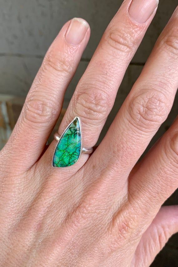 A stunningly sparkly green monarch sterling opal has been set in sterling silver with a handmade ring band from sterling silver half dome wire. This stone is just gorgeous and bright with varying hues of blue and green and elegant black veining throughout the stone. The stone is 21mm x 10mm in size.Size 5-5.5.Monarch sterling opal chatoyant gemstones are synthetic opals but created in a highly specialized design and technique. Its trademark is the abundance of colors and the black lines running Adjustable Silver Jewelry With Natural Inclusions, Sterling Silver Jewelry With Natural Inclusions For Anniversary, Opal Gemstone Ring As A Gift, Adjustable Fine Jewelry Opal Ring, Green Opal Cabochon Ring, Polished Chrysoprase Ring Jewelry, Green Opal Wedding Jewelry, Unique Green Opal Promise Ring, Adjustable Iridescent Sterling Silver Jewelry