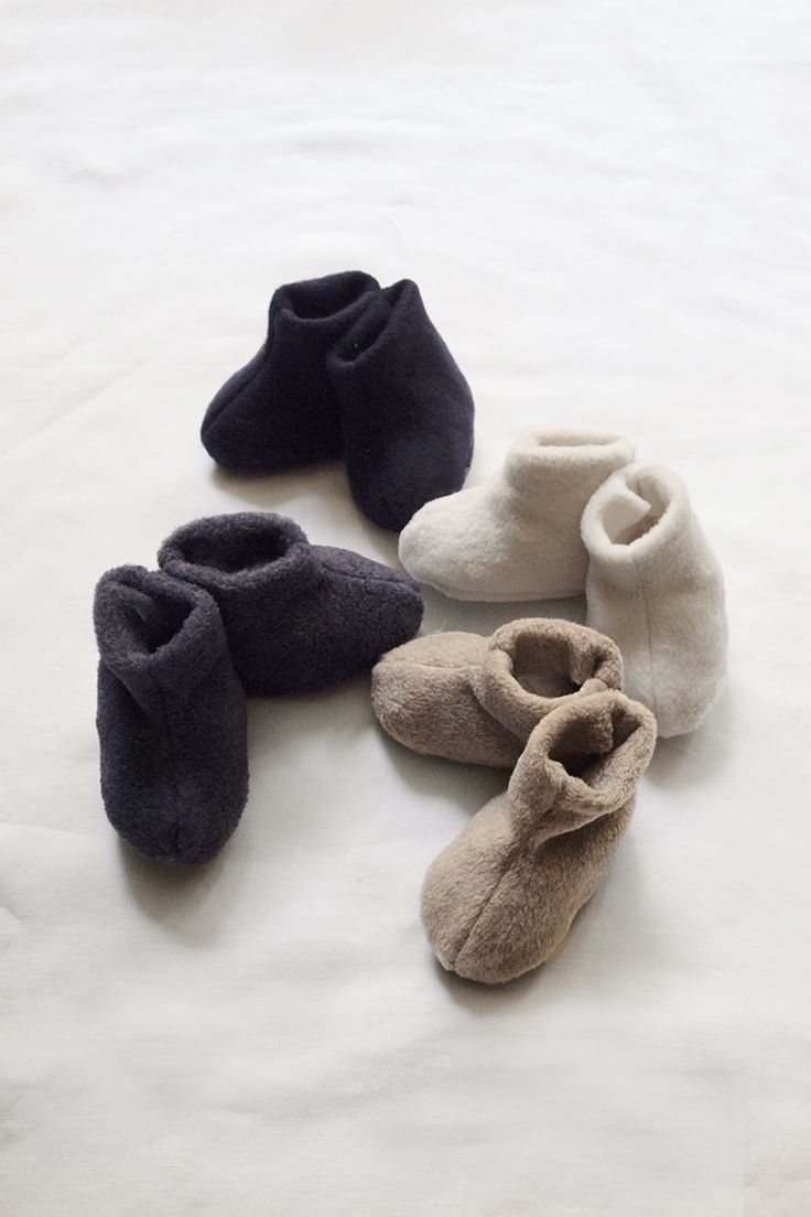 several pairs of baby shoes are laid out on a bed