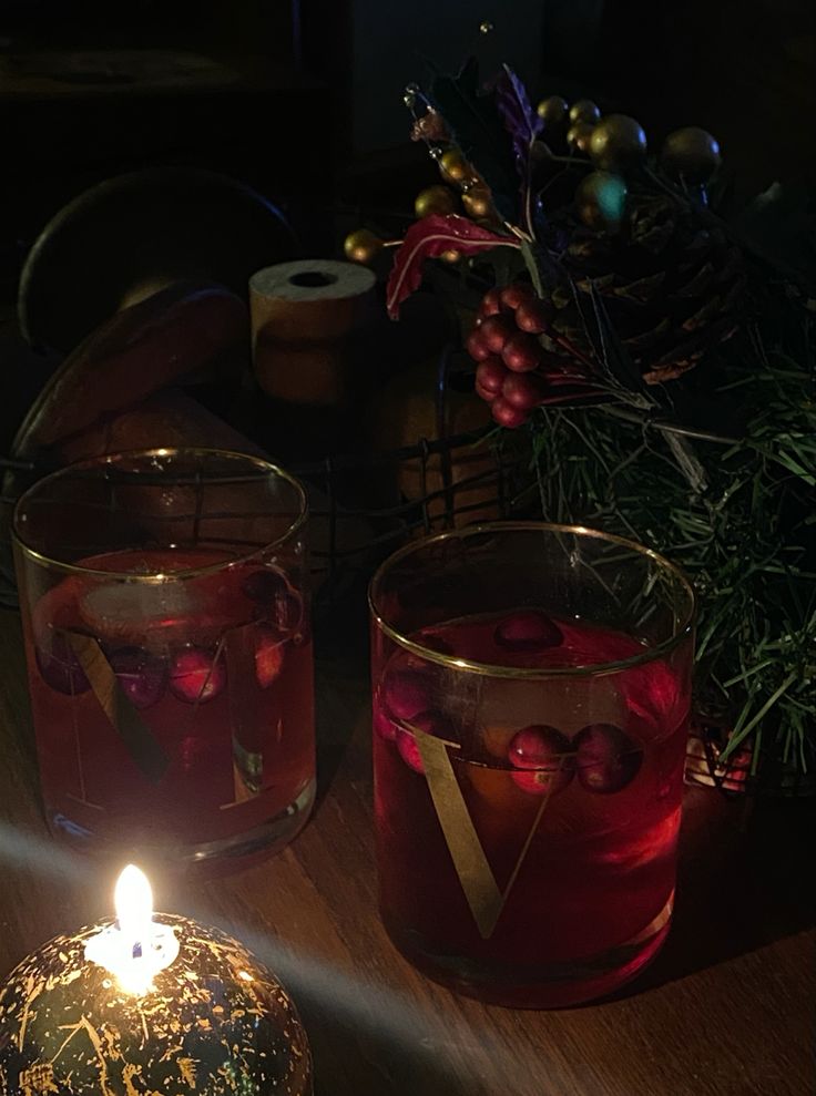 two candles sitting on top of a wooden table next to christmas decorations and other items