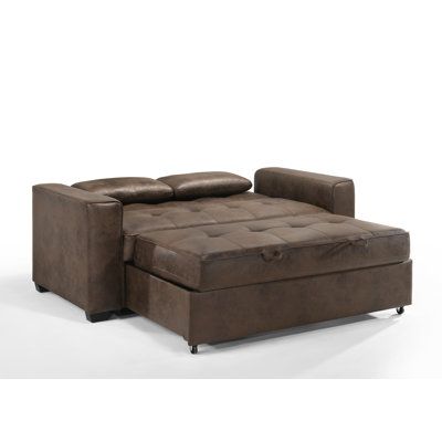 a brown leather couch sitting on top of a white floor next to a footstool