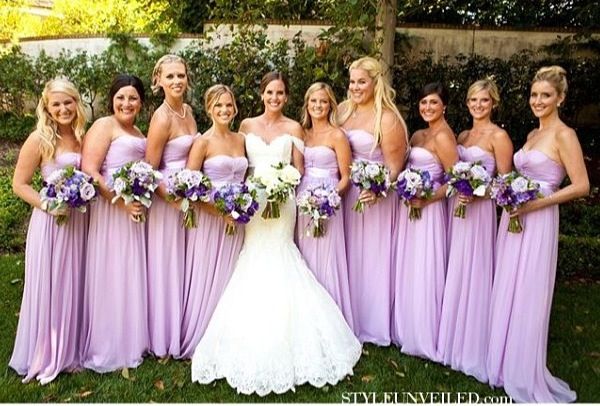 a group of women standing next to each other wearing purple dresses and holding bouquets