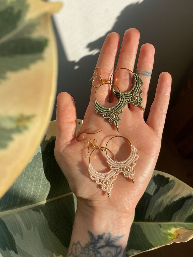 a woman's hand with tattoos holding several pairs of hoop earrings on her wrist