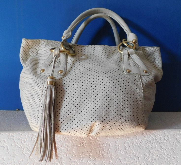 "Great looking leather shoulder bag Beige leather perforated as shown Tassel Gold is seen through perforation Gold tone hardware 3 magnet snap closure 1 zipper interior compartment, 1 open compartment Normal wear sign but condition is great for the age Dimension - height 12\" length 17\" depth 6.5\" strap 8\"" Chic Shopping Bags With Perforations, Chic Shopping Bag With Perforations, Chic Tote Bag With Perforations, Leather Bags With Perforations For Everyday Use, Leather Bag With Perforations For Daily Use, Perforated Tote Shoulder Bag For Everyday Use, Everyday Perforated Tote Shoulder Bag, Everyday Use Tote Shoulder Bag With Perforations, Everyday Tote Shoulder Bag With Perforations