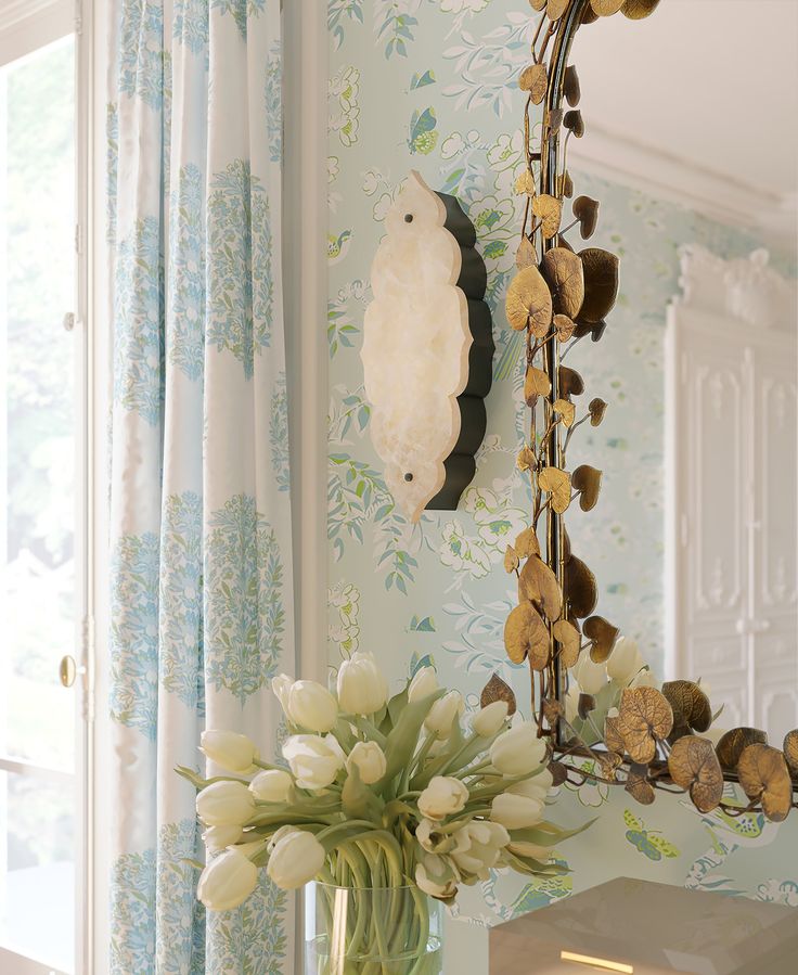 a vase filled with flowers sitting on top of a table next to a mirror and window