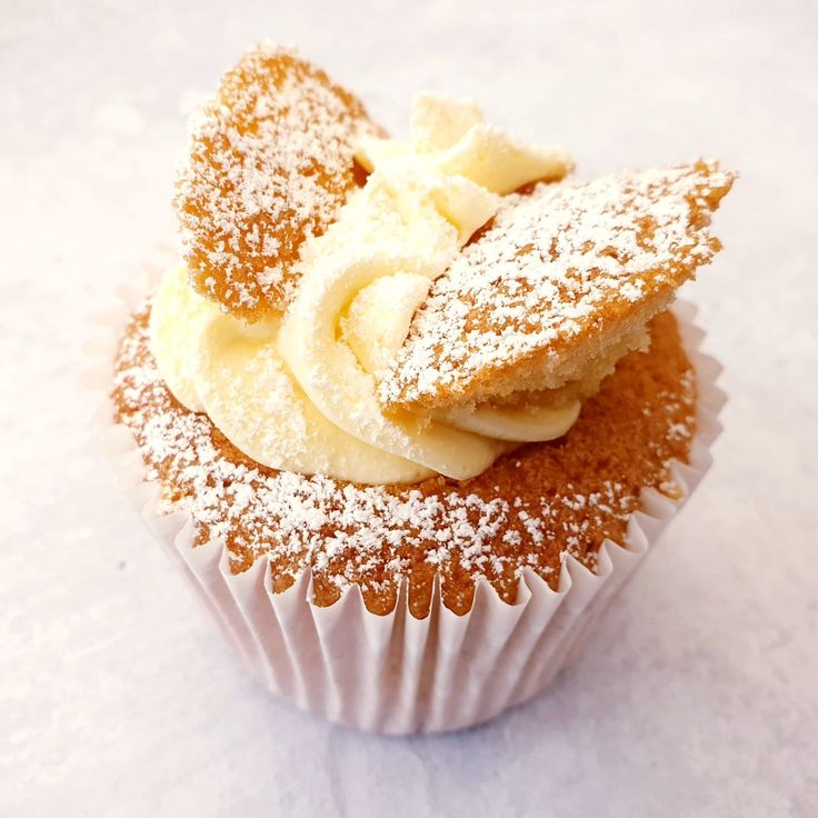 a cupcake with powdered sugar and bananas on top is sitting on a white surface