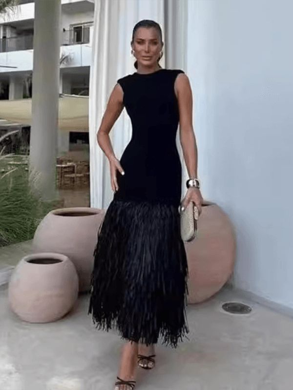 a woman in a black dress standing next to a large vase and holding a purse