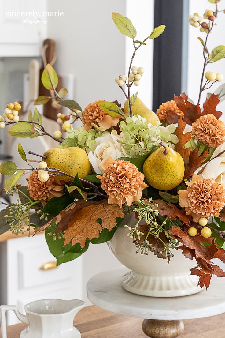 a vase filled with fruit and flowers on top of a table