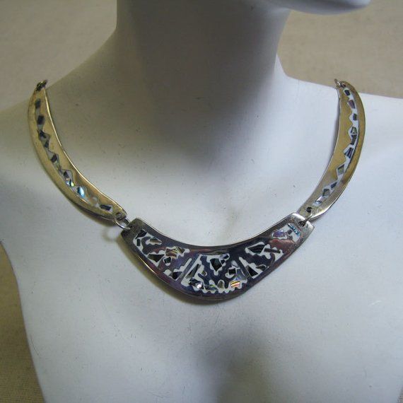 This handsome multi piece necklace features the incredible work of the Mexican metalsmiths. It is made of alpaca metal which looks like silver and wears like iron. The metal is an alloy with zinc, copper and sometimes nickel. The inlay work is lustrous pieces of abalone shell which are the color of a stormy sky but radiate colors of blue, green and pink. The background is white enamel in the metal which makes this a perfect spring or summer necklace. The necklace measures 17 inches long and each Artisan Silver Etched Necklace, Artisan Metal Jewelry With Etched Details, Unique Silver Etched Necklaces, Unique Etched Metal Jewelry, Artisan Etched Metal Jewelry, Artisan Silver Engraved Necklaces, Silver Hand Forged Metal Necklace, Hand Forged Silver Metal Necklace, Unique Engraved Metal Jewelry