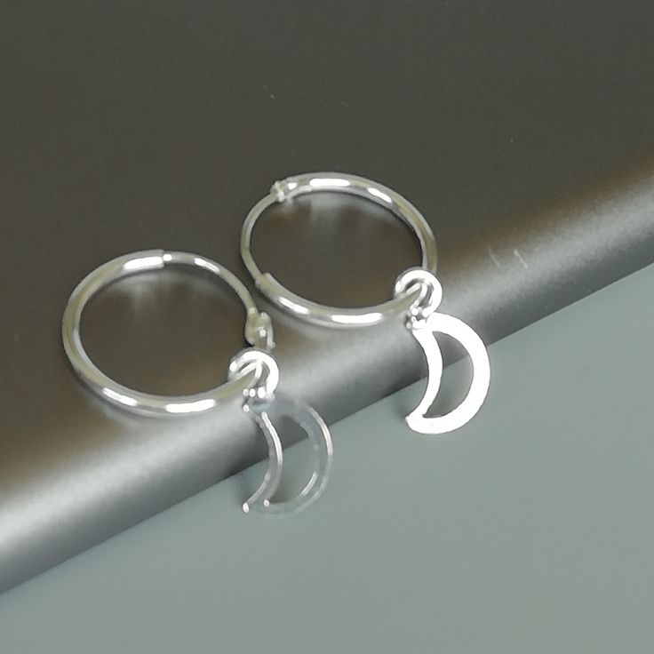 A PAIR of sterling silver hoops. Comes with a detachable cut out crescent moon charm. The charm is multipurpose and can be used with a neck or bracelet chain too. Dimension: Hoop- 15 x 1.5 mm Charm: 6 x 12 mm Drop length- 23 mm These earrings are made of 925 hypoallergenic sterling silver and plastic. Please note this price is for ONE PAIR. All my pieces are sent in a gift box. I can include a personal message from you if needed You are welcome to contact me at... bhavnakwintra1956@gmail.com For Minimalist Moon-shaped Sterling Silver Cartilage Earrings, Minimalist Sterling Silver Hoop Earrings With Moon Charm, Sterling Silver Moon Charm Earrings For Everyday, Small Silver Hoop Earrings With Moon Charm, Silver Small Hoop Earrings With Moon Charm, Sterling Silver Crescent Cartilage Earrings With Moon Charm, Silver Minimalist Moon Cartilage Earrings, Silver Moon Charm Earrings For Everyday, Silver Hoop Earrings With Moon Charm