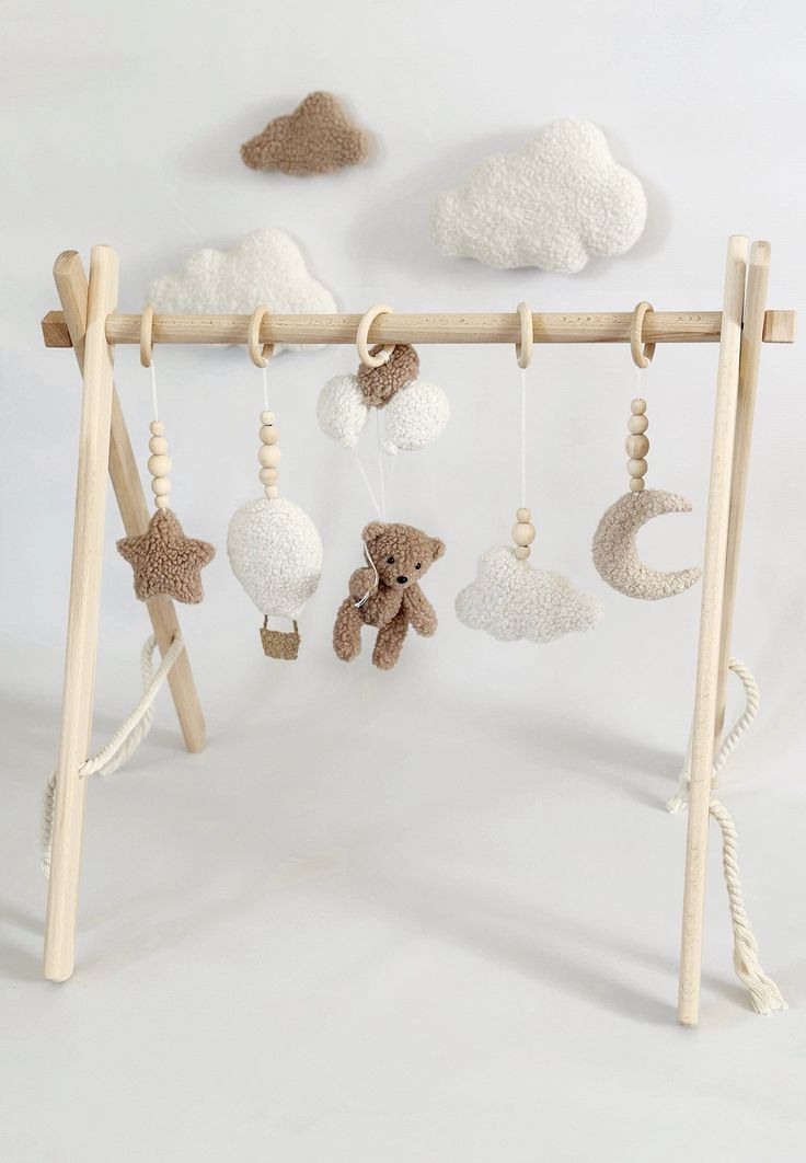 a baby crib with stuffed animals hanging from it's sides and clouds in the background