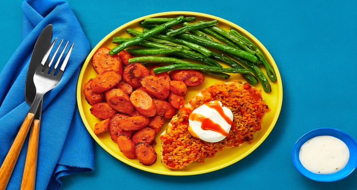 a yellow plate topped with meat and green beans next to a blue bowl filled with sauce