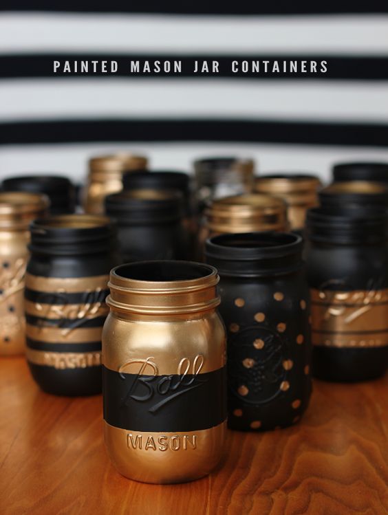 some jars are sitting on a table with gold and black paint in the jar, which is