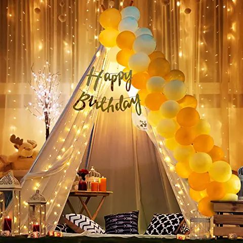 a birthday party with balloons and lights on the wall, in front of a teepee tent