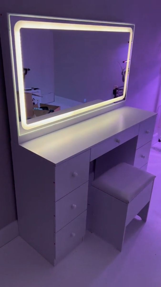 a white vanity with a lighted mirror and stool