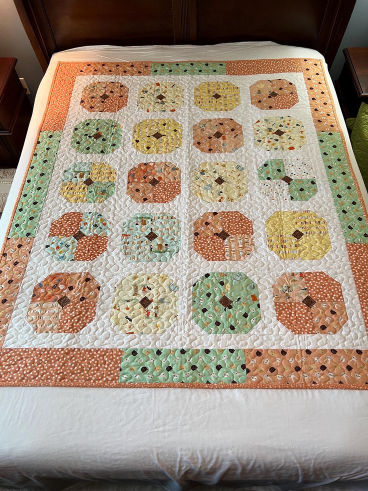 a quilted bedspread with an orange and green design on the bottom half