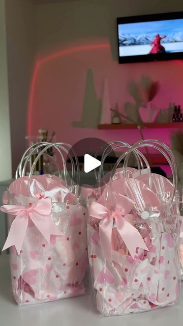 three bags with pink bows on them sitting on a table in front of a television