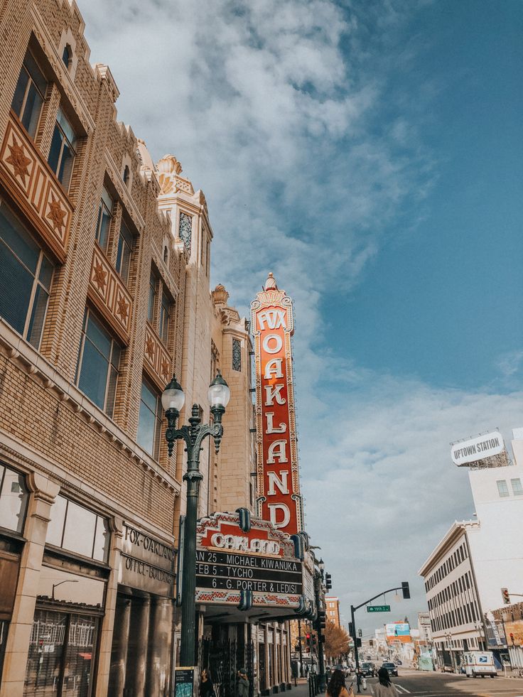 people are walking on the sidewalk in front of an old building with a sign that says oakland