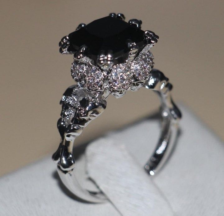 a black diamond ring sitting on top of a white napkin