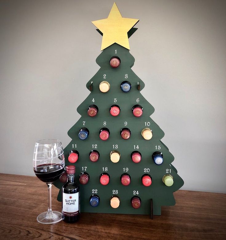 a wooden christmas tree with wine glasses next to it