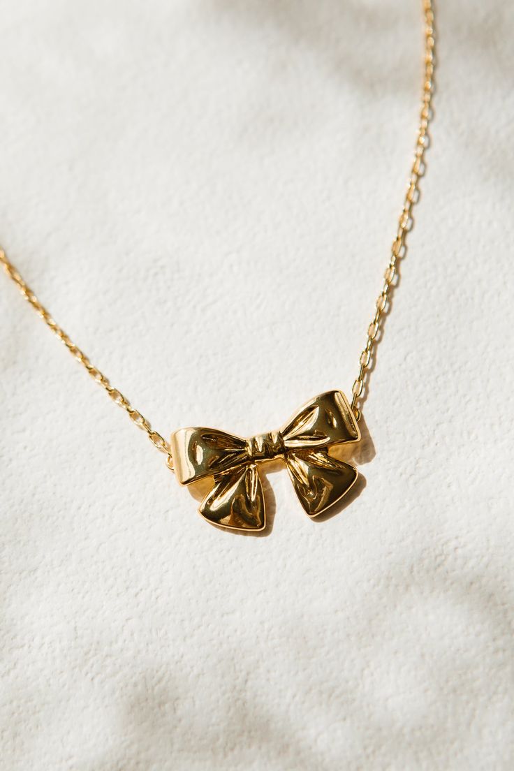 Add some whimsy to your jewelry collection with our Gold Bow Necklace. This playful piece features a delicate gold chain and a charming bow charm. With its convenient lobster closure, you'll never have to worry about losing this stylish accessory. Perfect for any occasion! Gold Bow Jewelry, Jewellery Lookbook, Josie Wedding, Bow Things, Everyday Gold Jewelry, Chunky Gold Necklace, Ballet Jewelry, Delicate Gold Chain, Gift Wishlist