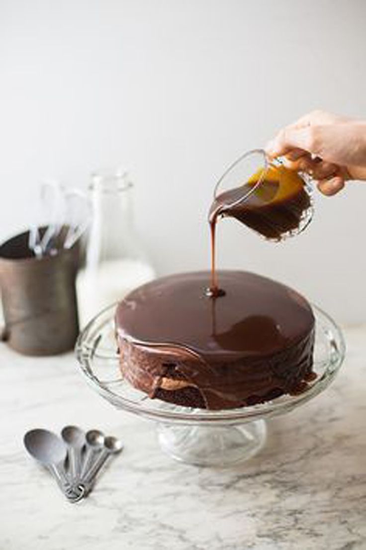 someone drizzling chocolate on top of a cake