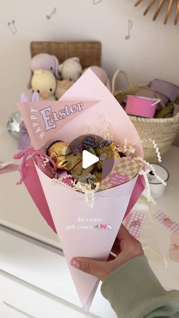 someone is holding up a pink box filled with chocolates and candies in it