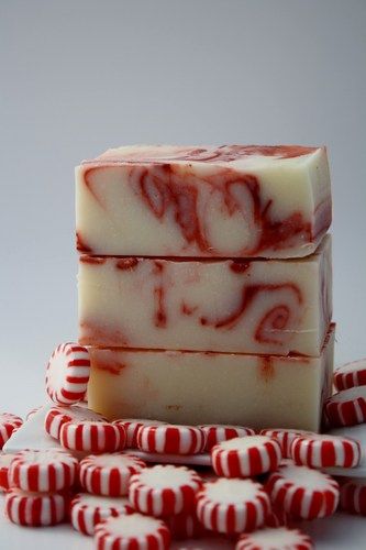 red and white candy canes next to two bars of soap on a white surface