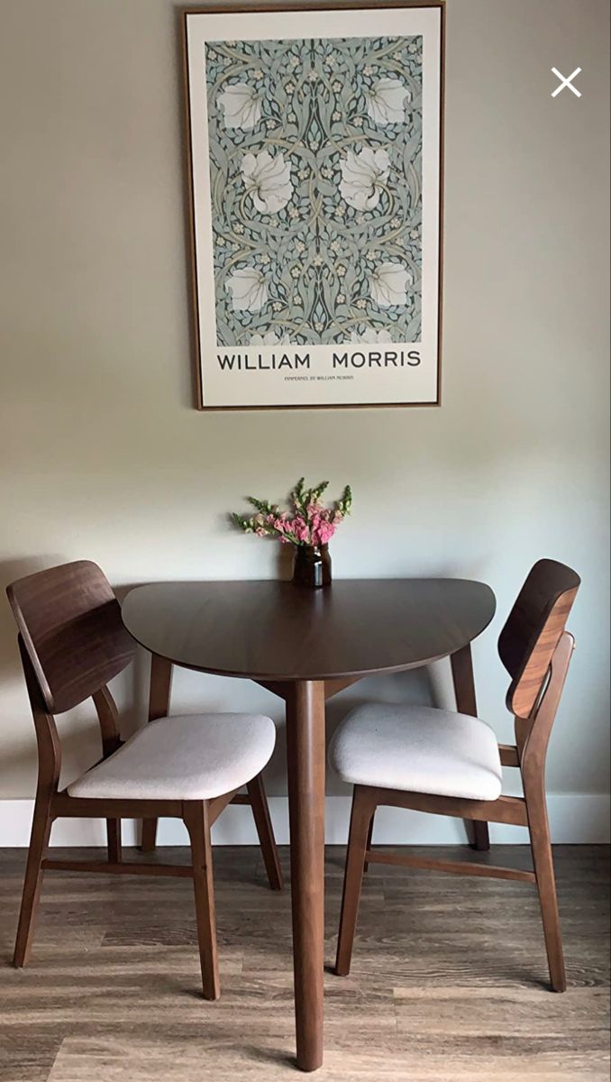 a dining room table with two chairs and a vase on the table next to it