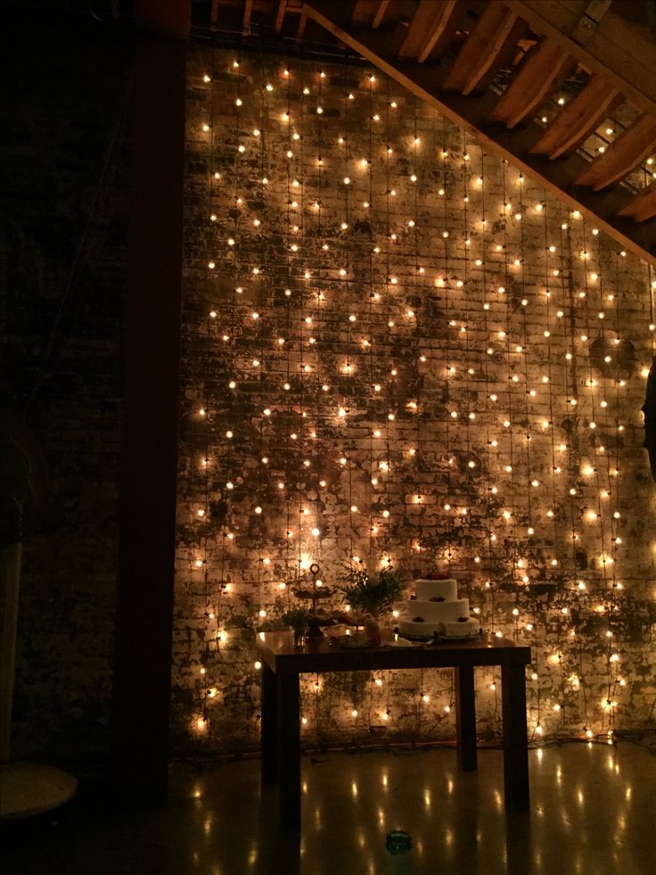 a man standing in front of a wall with lights all over it and a laptop on a table