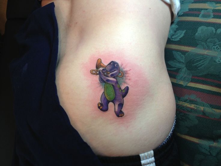 a woman with a tattoo on her stomach has a small cartoon character tattooed on her belly