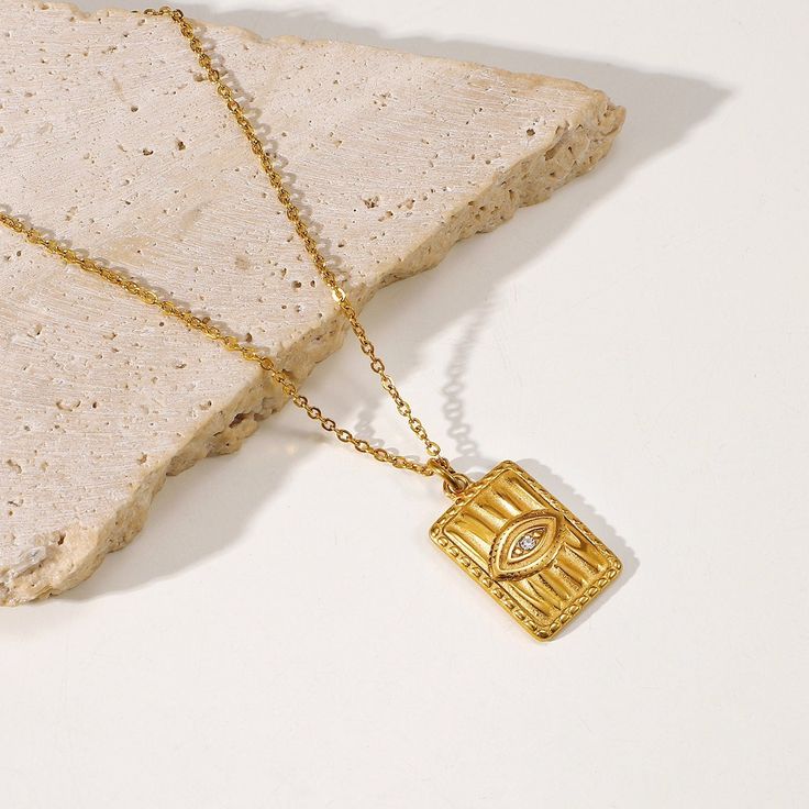 Inspired by ancient symbolism, the Egyptian Eye Necklace, in 18k gold plating, is a captivating accessory. Its intricate design symbolizes protection and wisdom, adding a touch of historical mystique to your fashion ensemble. Symbolic Gold Plated Engraved Necklaces, Symbolic Engraved Gold Plated Necklaces, Symbolic Gold Plated Locket Necklace, Gold Symbolic Square Pendant Jewelry, Symbolic Gold Square Pendant Jewelry, Symbolic Gold Jewelry With Square Pendant, Brass Amulet Necklace, Gold Amulet Charm Necklace Tarnish Resistant, Symbolic Gold Brass Charm Necklaces