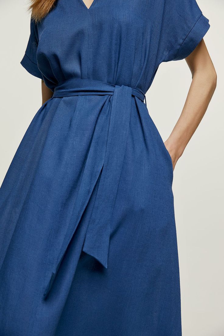 This blue summer midi dress is crafted in linen style fabric. It has short drop sleeves and a deep V neckline. There is a vertical seam in the front.  It has belt loops at the waist with a belt in the same fabric creating the perfect fit. The hem is slightly rounded. The dress is styled in a loose A line silhouette. Gentle machine wash. Turn garment inside out. Cold water. Mild detergent. Iron on reverse side. Do not tumble dry. Do not bleach. Blue Belted Short Sleeve Maxi Dress, Blue Knee-length Belted Summer Dress, Linen Midi Dress With Tie Waist, Linen Midi Dress With Tie Waist For Daywear, Chic Blue Linen Maxi Dress, Blue Belted Summer Dress, Blue Belted Midi Dress With Short Sleeves, Blue Short Sleeve Belted Midi Dress, Summer V-neck Belted Dress For Daywear