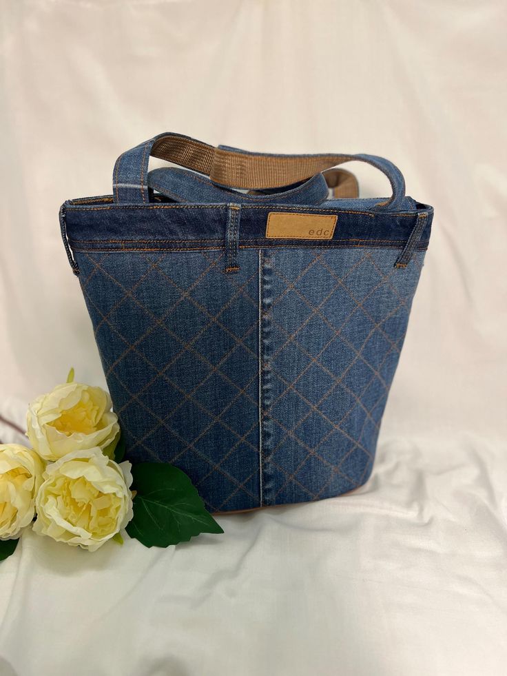 a blue denim bag with flowers on the side and a white cloth background behind it