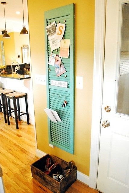 a green door that has some papers on it in front of a kitchen with stools