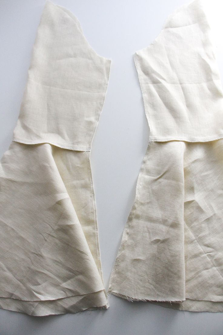 two pieces of white cloth folded together on top of each other with one piece torn off