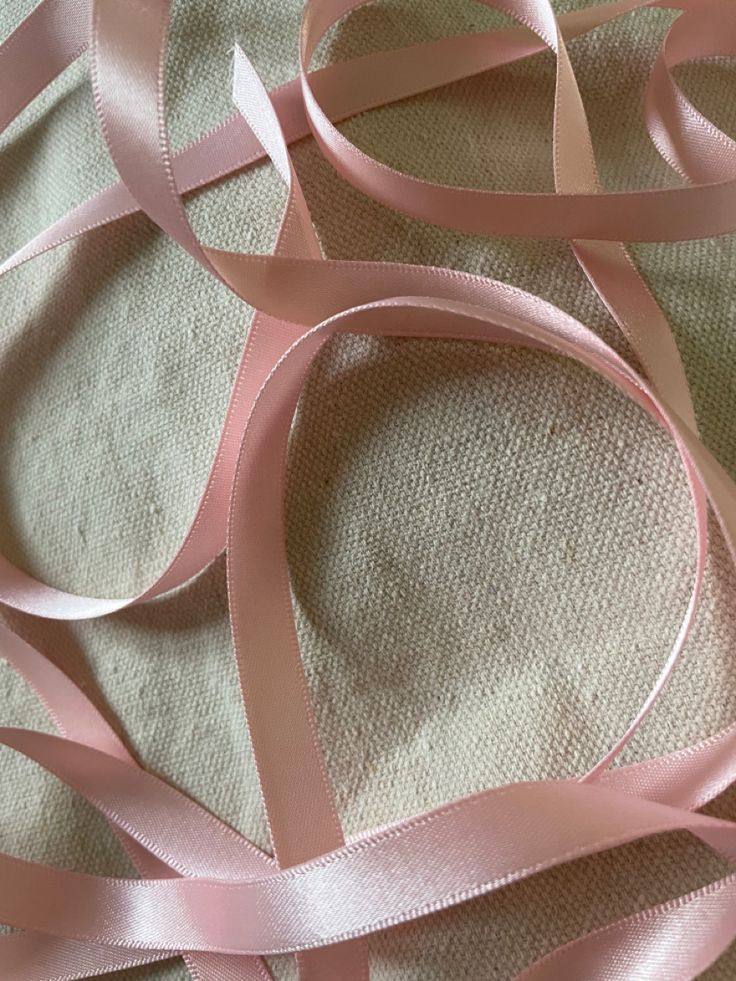 pink satin ribbon on white fabric with no other material in the photo to be seen