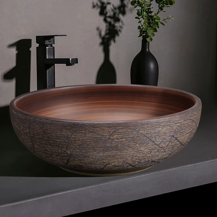 a wooden bowl sink sitting on top of a counter next to a vase with flowers