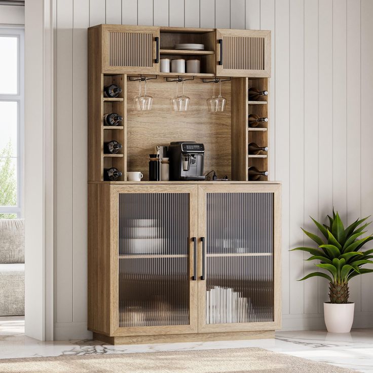 a wooden cabinet with glass doors and shelves in a room next to a potted plant