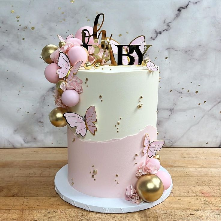 a pink and white cake with gold decorations on it's side, sitting on a wooden table