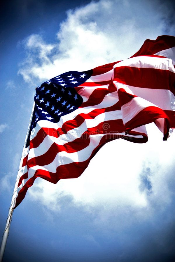 an american flag blowing in the wind on a sunny day with blue sky and clouds