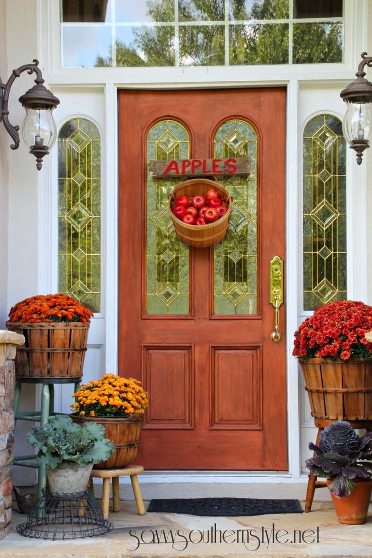 the front door is decorated with flowers and baskets full of fresh fruit for fall decor